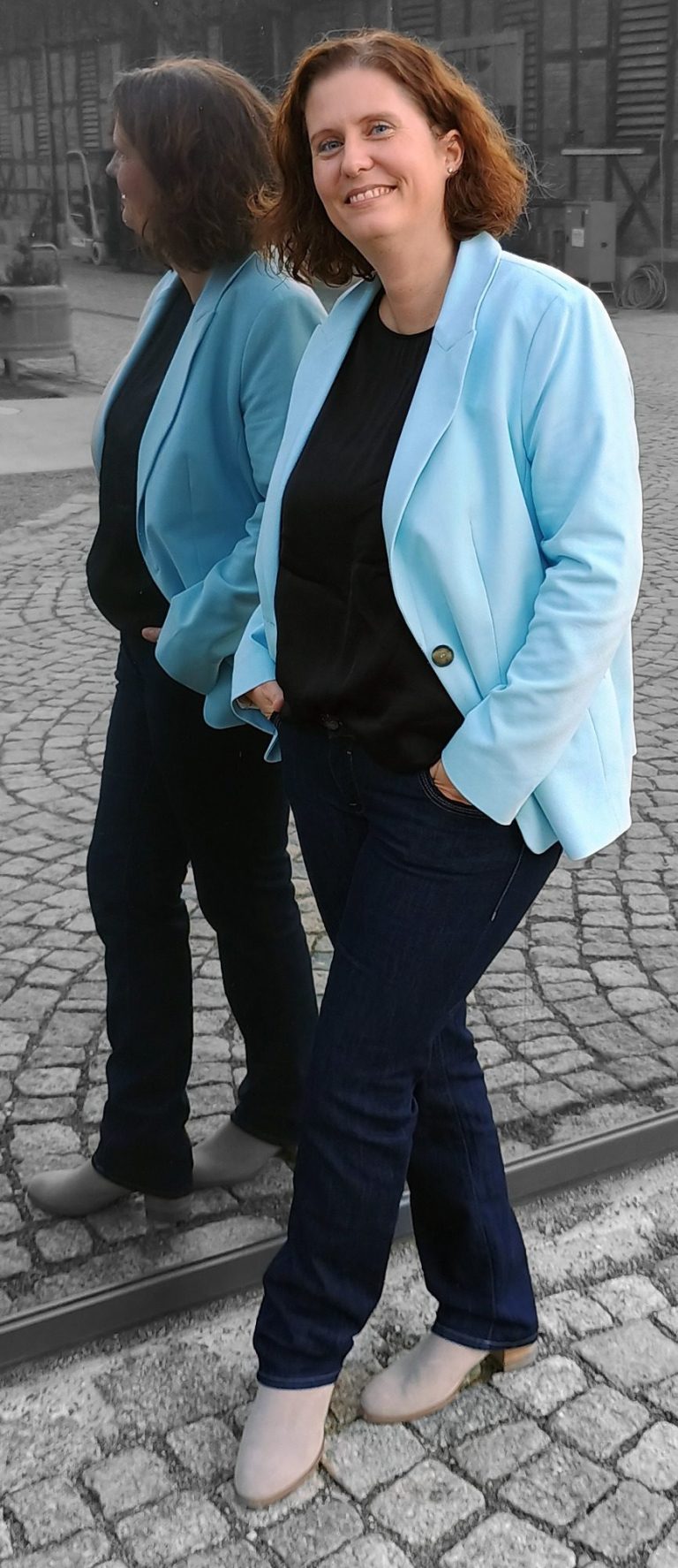 Spiegelbild Heike Goller-Lenz steht vor einer Glasfläche, sie spiegelt sich darin